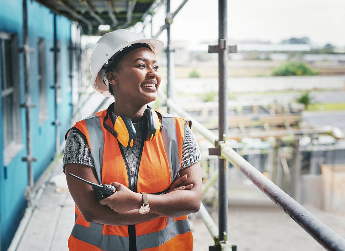 Insurance by Industry - A Young Female Contractor Looking Off Into the Distance While Wearing a Safety Hat and a Safety Vest
